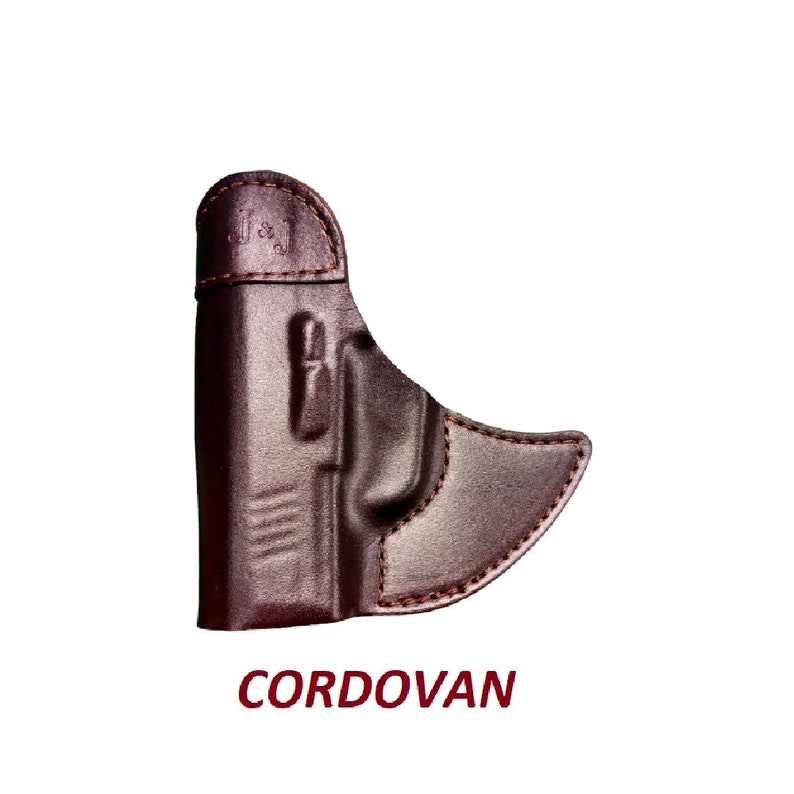 May include: A brown leather holster for a handgun. The holster is made of cordovan leather and has a smooth finish. The holster is designed to fit a compact or subcompact handgun.