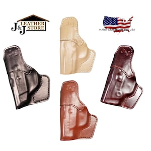 May include: Four leather gun holsters in various colors: black, tan, brown, and burgundy. Each holster is stamped with "J & J" and the text "HAND CRAFTED IN THE USA" is visible.