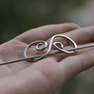 May include: Silver hair stick with a decorative swirl design.