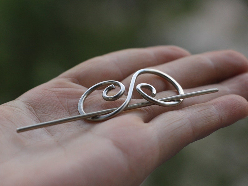 May include: Silver hair stick with a decorative swirl design.