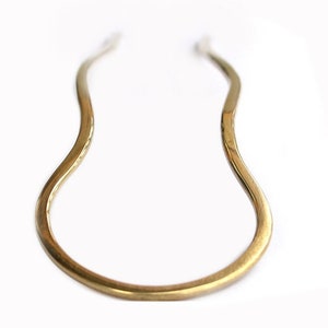 May include: A gold-colored metal hair pin with a wavy design.