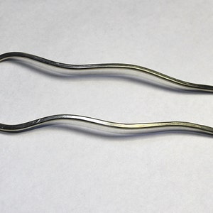 May include: A silver metal hair comb with a wavy design.