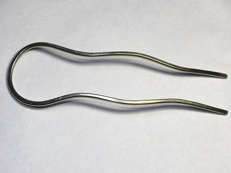 May include: A silver metal hair comb with a wavy design.