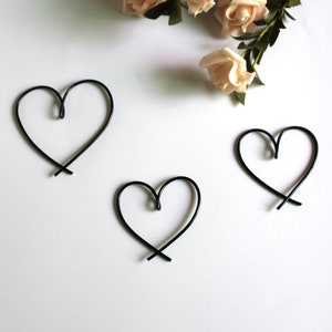 May include: Three black wire heart shapes on a white background.