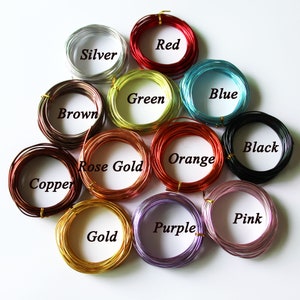 May include: A collection of coiled wire in various colors, including silver, red, blue, black, and gold. Each coil is labeled with its color name. The wires are likely for crafting or jewelry making.