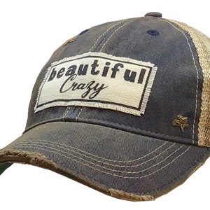 May include: A blue and brown distressed trucker hat with a white patch that says "beautiful crazy" in black lettering.