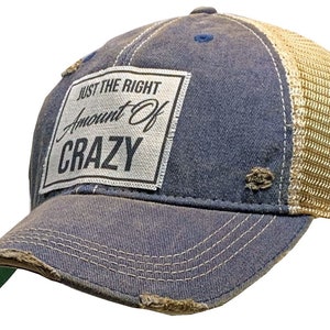 May include: A blue and beige distressed trucker hat with a white patch that reads "Just the Right Amount of Crazy".