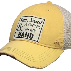 May include: Yellow distressed trucker hat with a beige mesh back. The hat has a square patch with the text "Sun, Sand & A Drink In My Hand".