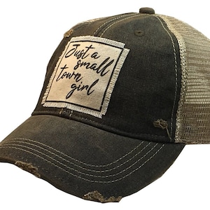 May include: A black and brown distressed trucker hat with a white patch that says "Just a small town girl".