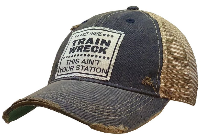 May include: A blue and brown distressed trucker hat with a white patch that reads "Hey There... Train Wreck... This Ain't Your Station".