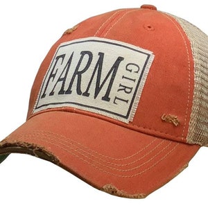 May include: A distressed orange and beige baseball cap with a white patch that says "FARM GIRL" in black lettering.