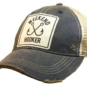 May include: A blue and beige distressed trucker hat with a white patch that says "Weekend Hooker" with two crossed fishing hooks.