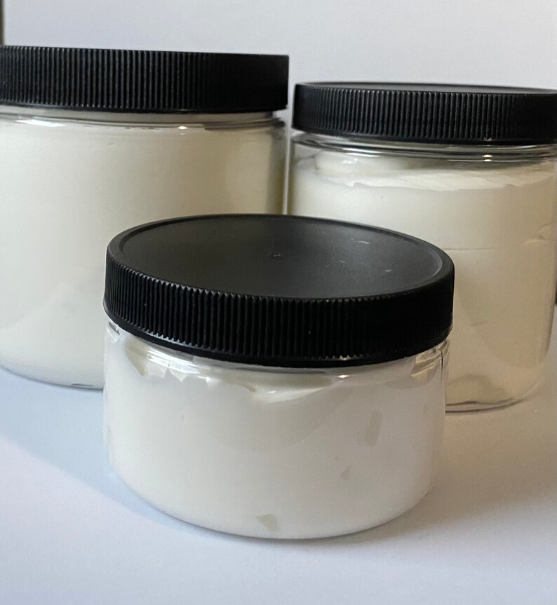 May include: Three clear plastic jars with black lids filled with white cream. The jars are different sizes.