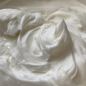 May include: Close-up of a white, creamy substance with a smooth, whipped texture.