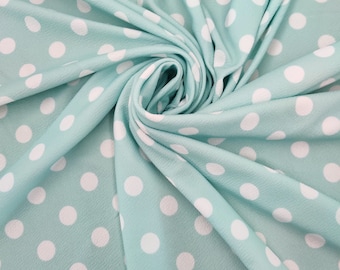 Peut inclure: Un tissu bleu clair à pois blancs. Le tissu est plié et drapé, créant un aspect doux et texturé.