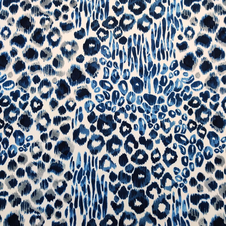 May include: A fabric with a repeating pattern of blue and gray leopard spots and vertical brushstrokes on a white background. The design features varying shades of blue, creating a textured and dynamic appearance. This textile is suitable for various applications.