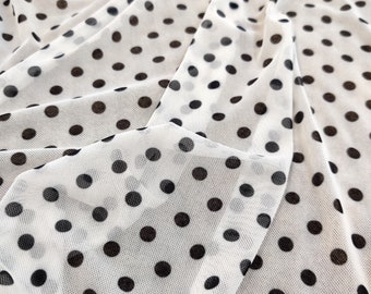 May include: White sheer fabric with black polka dots. The fabric is gathered and draped, showing the texture of the mesh.
