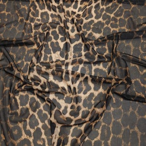 May include: A sheer fabric with a leopard print pattern. The fabric features a dark brown background with tan and brown spots. The material is draped, showing the texture and pattern of the fabric. This textile is suitable for apparel and craft projects.