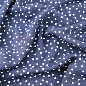 Peut inclure: Gros plan sur un tissu bleu marine &agrave; pois blancs. Le tissu est froiss&eacute; et a une texture douce.
