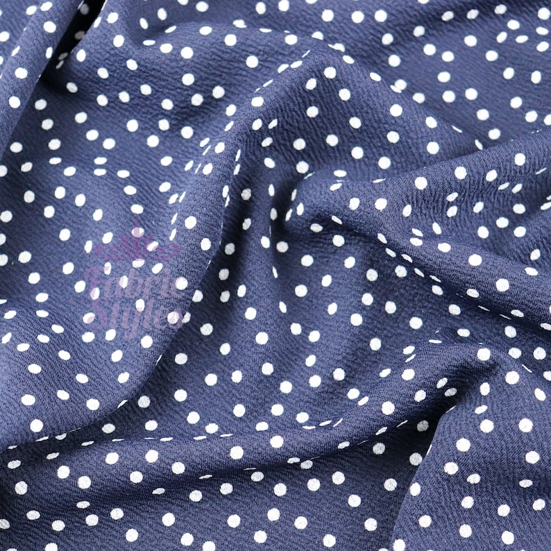 Peut inclure: Gros plan sur un tissu bleu marine &agrave; pois blancs. Le tissu est froiss&eacute; et a une texture douce.