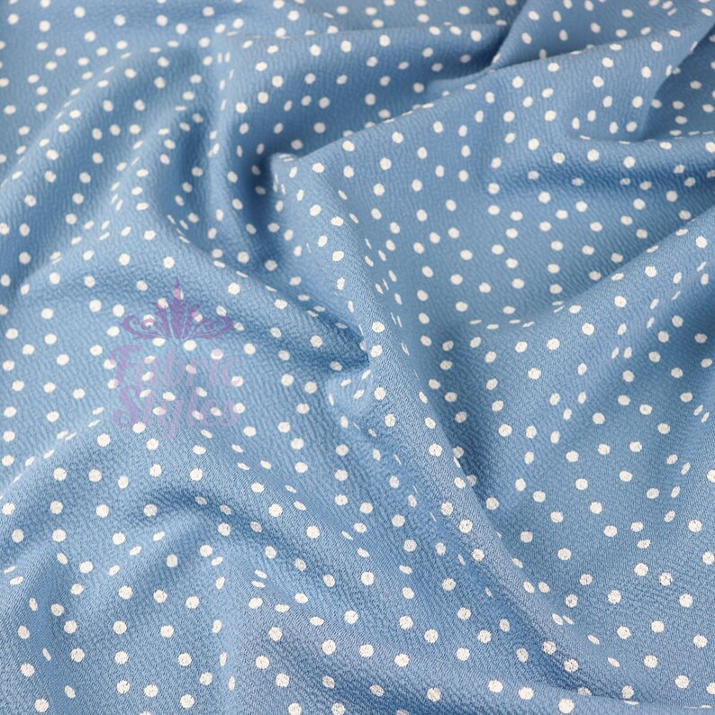 Peut inclure: Un gros plan sur un tissu bleu avec des pois blancs. Le tissu est froiss&eacute; et a une surface textur&eacute;e.