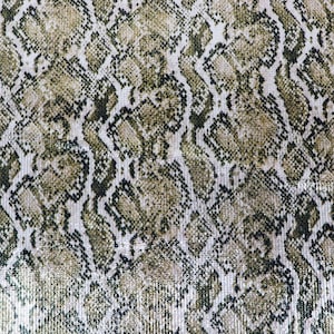 Op de afbeelding: Een stof met een herhalend slangenpatroon in tinten olijfgroen, beige en zwart. Het oppervlak is bedekt met kleine, reflecterende pailletten die een glinsterend effect creëren over het gehele gestructureerde materiaalontwerp.