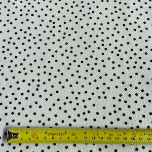 Peut inclure: Tissu blanc &agrave; pois noirs. Le tissu est mesur&eacute; avec un m&egrave;tre ruban jaune.