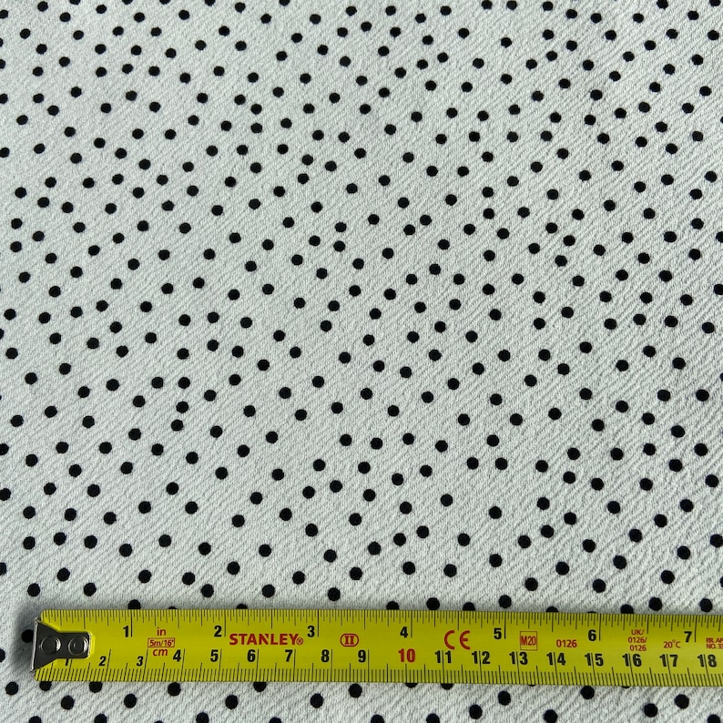 Peut inclure: Tissu blanc &agrave; pois noirs. Le tissu est mesur&eacute; avec un m&egrave;tre ruban jaune.