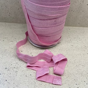 May include: Pink elastic ribbon with a shimmery finish. The ribbon is rolled up and a few strands are loose.