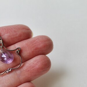 May include: A silver wire pendant with a delicate design featuring a light purple amethyst gemstone.