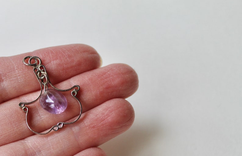 May include: A silver wire pendant with a delicate design featuring a light purple amethyst gemstone.