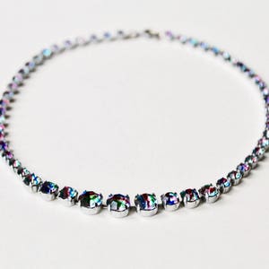 May include: A silver necklace featuring iridescent stones. The stones are set in a row and are linked by a thin silver chain.
