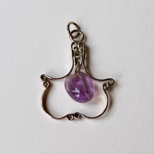 May include: A silver pendant with a delicate, openwork design, featuring a purple amethyst gemstone.