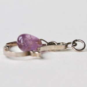 May include: A silver charm bracelet with a purple amethyst stone charm.