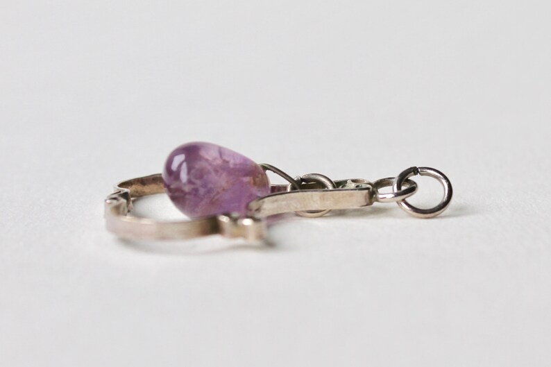 May include: A silver charm bracelet with a purple amethyst stone charm.