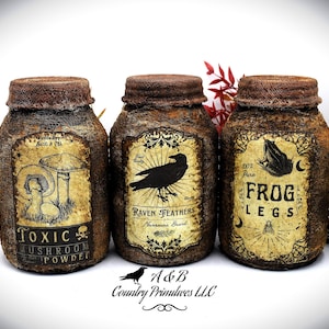 May include: Three rustic jars with aged labels, featuring the text "Toxic Mushroom Powder," "Raven Feathers," and "Frog Legs." Each jar has a textured, brown exterior and a matching lid. The labels include illustrations of mushrooms, a raven, and a frog.