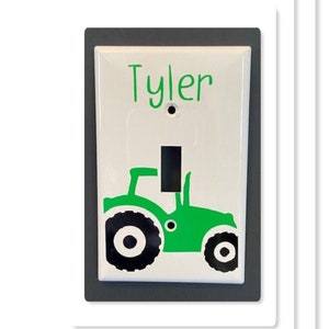 May include: A white light switch cover with a green tractor design and the name "Tyler" written in green lettering.