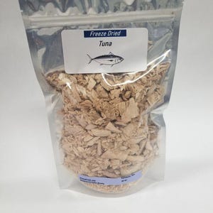 May include: A clear plastic bag with a resealable zipper closure contains freeze-dried tuna. The bag has a label that reads "Freeze Dried Tuna".