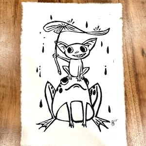 May include: Black and white illustration of a frog holding an umbrella over a small creature with large ears. The creature is smiling and holding the umbrella handle. The image is on a white background.