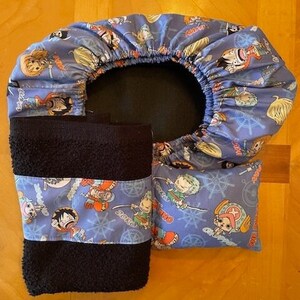 May include: A blue and white fabric shower cap with a black towel and a blue and white pillow with a cartoon character print. The pillow has the text "Zoro" and "Luffy" on it.