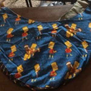 May include: A blue fabric tote bag with a repeating pattern of yellow cartoon characters. The characters are wearing red shirts and blue pants.