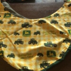 May include: Yellow and green baby burp cloth with a repeating pattern of John Deere tractors and logos.