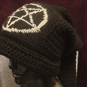 May include: Black knitted hat with a white pentagram design and a long black tassel.
