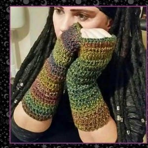 May include: A pair of fingerless gloves featuring a variegated crochet pattern in earthy tones of forest green, deep brown, and hints of golden yellow. The gloves have a textured, chunky knit construction that covers the forearms and hands.