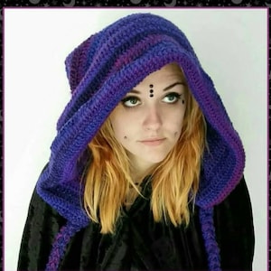 May include: A hooded cowl crafted from crocheted yarn in alternating shades of deep purple and blue. The hood features a textured, ribbed stitch pattern throughout, with long, dangling braided ties extending from the front edges of the garment.
