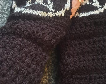 May include: Black crochet fingerless gloves with a white and silver pentagram design. The gloves have a textured stitch pattern and are likely handmade. The gloves are a gothic accessory.