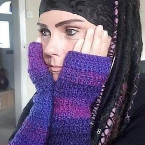 May include: A pair of fingerless gloves featuring a textured crochet knit pattern in a gradient of deep purple, magenta, and blue hues. The gloves extend from the knuckles down to the wrists, showcasing a consistent, dense stitch throughout the design.
