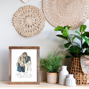 May include: A framed print with a watercolor illustration of the Holy Family. The image shows Mary, Joseph, and baby Jesus. The text below the image reads "Holy Family, Pray for Us".