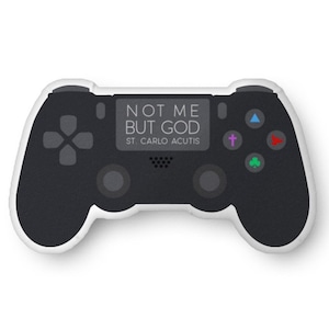 May include: A black and white video game controller with the text "NOT ME BUT GOD ST. CARLO ACUTIS". The controller has a directional pad, buttons, and joysticks. The design is a unique blend of gaming and faith.