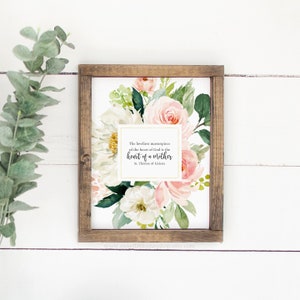 May include: A framed print featuring a watercolour floral design in shades of pink and white. The print includes a quote by St. Th&eacute;r&egrave;se of Lisieux: "The loveliest masterpiece of the heart of God is the heart of a mother."